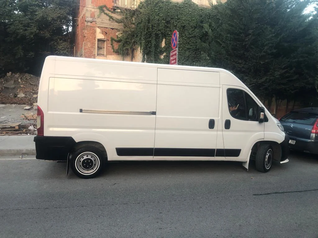 Şehir içinde beyaz panelvan, yandan görünüm